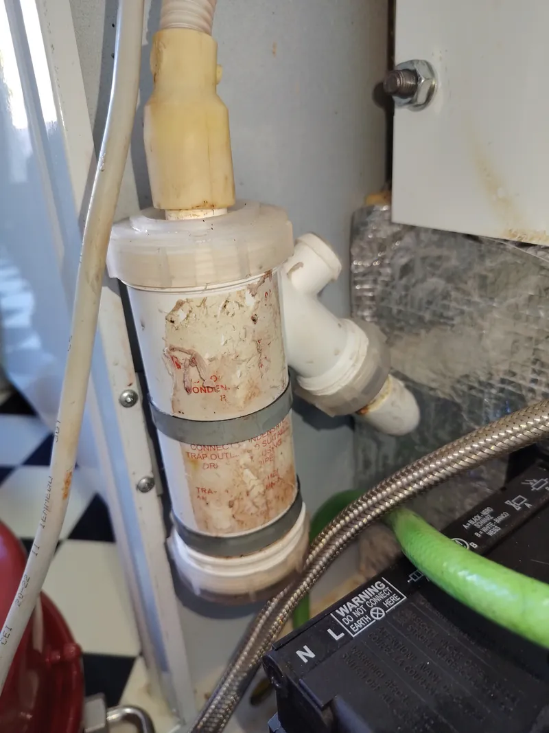 Condensate trap on a Grant Vortex Pro oil boiler before cleaning, coated in white and brown deposits