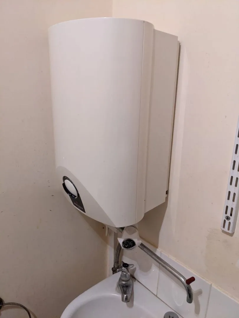 Wall-hung electric water heater fitted above a basin at Saltrock in Sidmouth
